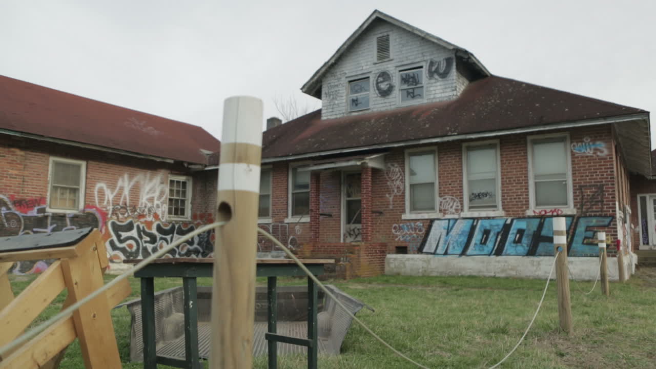 A dilapidated sign outside of a foreclosed and abandoned house