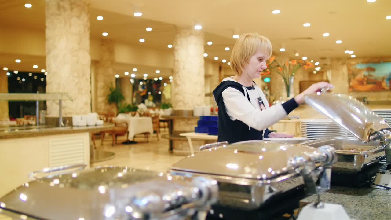 mujer pone verduras en los platos de la cafetería con autoservicio