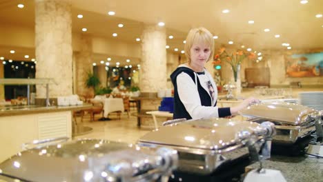 mujer pone verduras en los platos de la cafetería con autoservicio