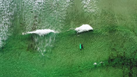 Two-surfers-in-the-sea,-top-view.-Norway-Lofoten-Islands