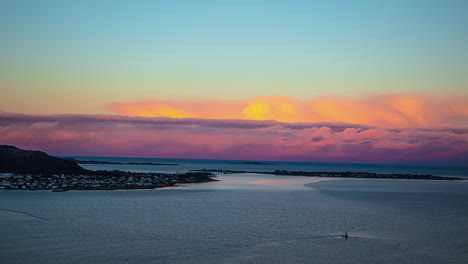 Vivid-pink-clouds-over-horizon,-sunrise-timelapse-from-fjord-at-Alesund,-Norway