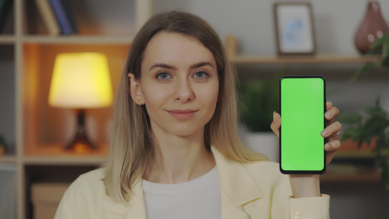 mujer sosteniendo un teléfono inteligente con pantalla verde