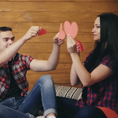 enamored man and woman are playing with cut out hearts of red color on the bed on the eve of saint valentine
