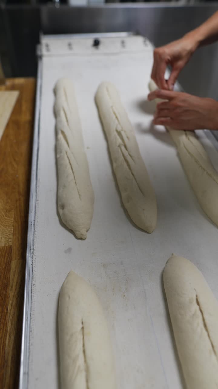 Baker shaping baguettes on a conveyor belt