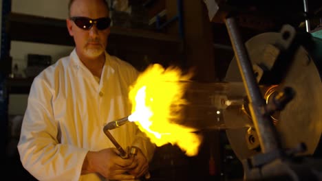 front view of mature male worker blowing glass in glass factory 4k