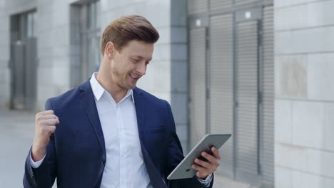 businessman reading good news on pad outdoors. employee enjoying success in city