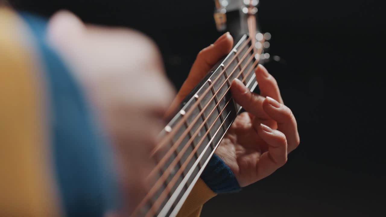 Primo piano di arpeggio melodico di chitarra acustica con movimenti delicati delle dita, luce calda da studio, cantautore che prova linee melodiche emotive, stato d'animo riflessivo e concentrato e fraseggio sottile