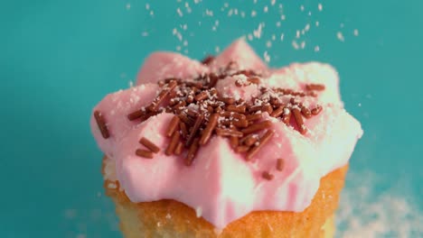 icing sugar being sieved on pink frosted cupcake