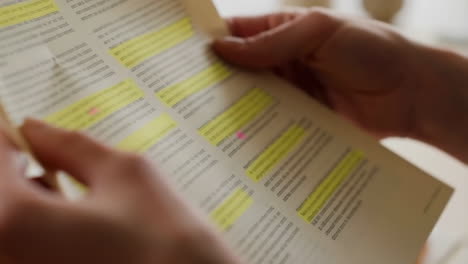 close-up of hands holding and highlighting text in a book