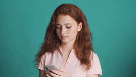 Redheaded-girl-in-front-of-camera-on-turquoise-background.