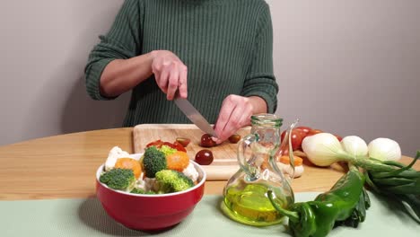 Woman-cutting-tomatoes-on-table-with-healthy-food