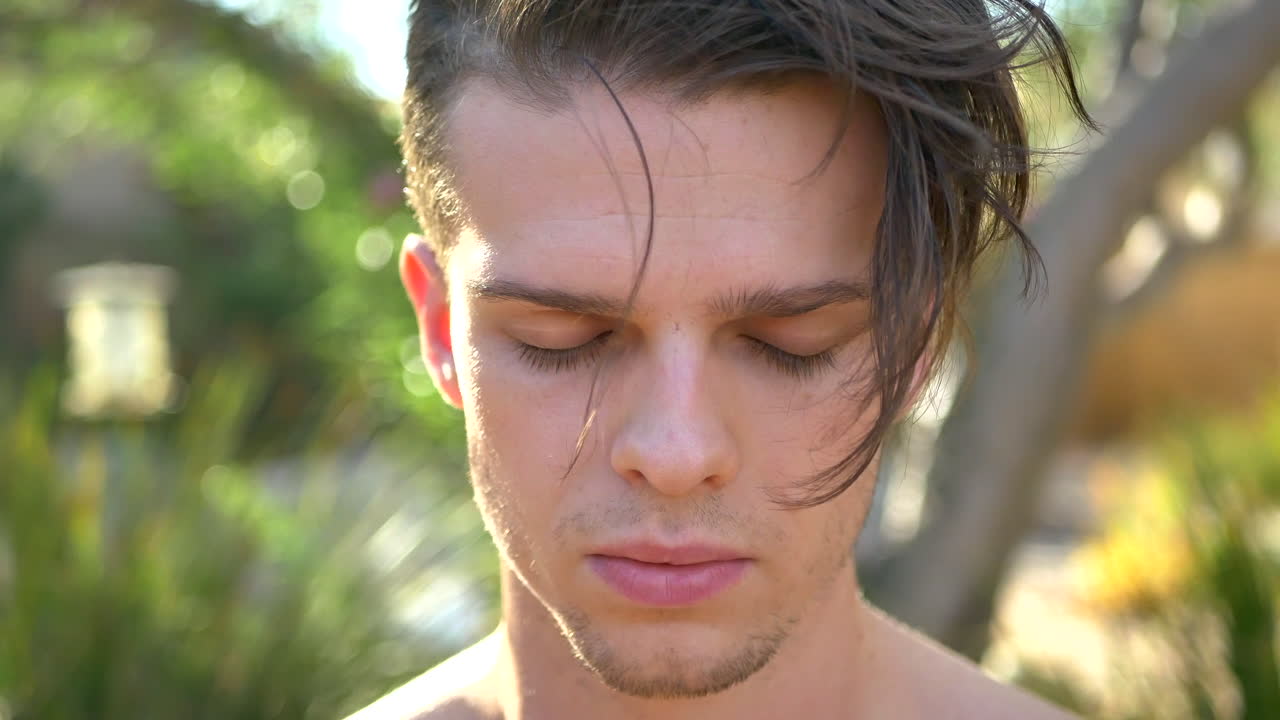 마음챙김, 현재의 자각, 양성에 집중하기 위해 명상에서 숨을 내쉬고 머리를 숙이고 있는 매력적인 젊은 백인 남자