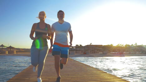 Pareja-Corriendo-En-El-Muelle-Del-Mar