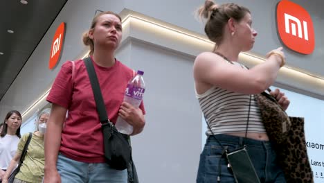 people walking past a xiaomi store in a city