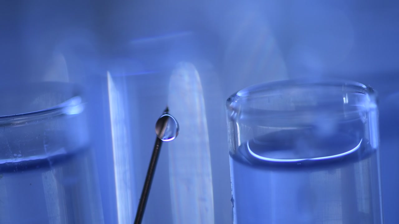 Toma macro de una gota de líquido expulsada de la aguja de una jeringa