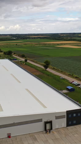 white commercial building among nature. modern industrial plant with cars nearby in a summertime. exterior of innovative center. aerial view. vertical video