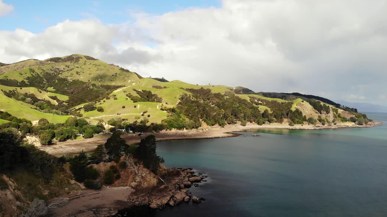 vista aérea de una montaña de hierba verde rodeada por un océano azul claro en kergi coromandel nueva zelanda, retroceder