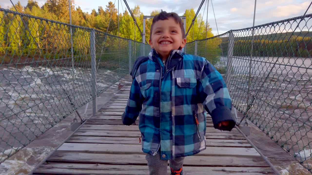 Anak kecil berlari di jembatan di hutan di Norwegia