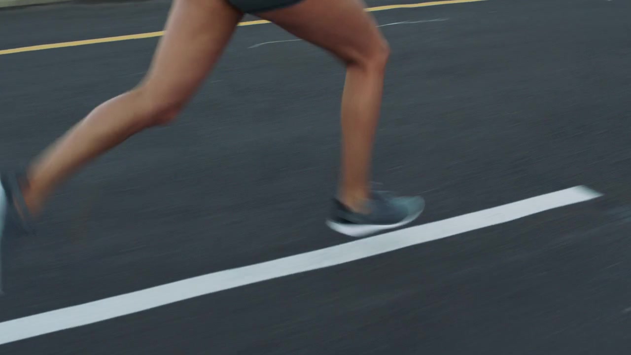 Primo piano delle gambe e dei piedi di un corridore su una pista di asfalto