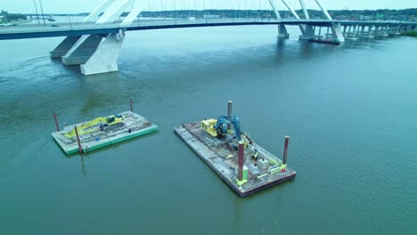 construction machineries on floating docks pontoon on mississippi river at centennial bridge in davenport, iowa, usa