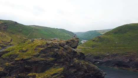 hikers on cornwall clifftop, united kingdom coastline, aerial arc shot