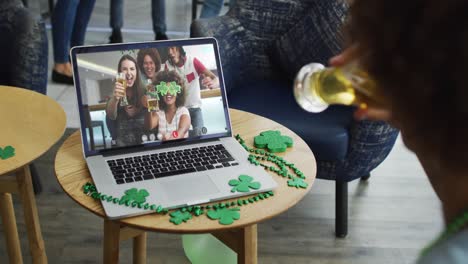 Man-having-beer-on-laptop-video-call-celebrating-st-patrick's-day-with-friends