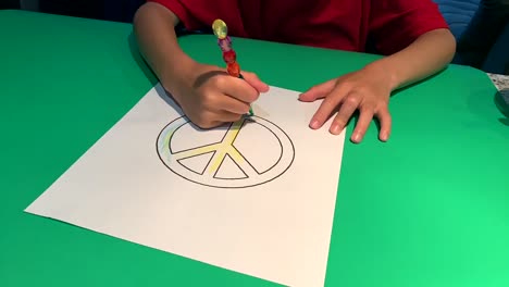 Manos-Pequeñas-Coloreando-Un-Signo-De-Paz-Y-Luego-Escribiendo-Las-Palabras-&quot;paz&quot;-Con-Un-Corazón-Alrededor