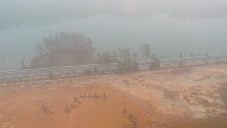 Toma-Aérea-En-La-Niebla-De-Dos-Lagos-De-Color-Diferentes-Separados-Por-Una-Carretera