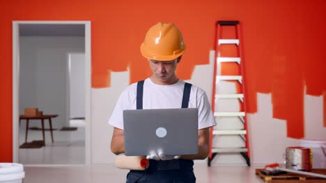 trabajador de la construcción usando una computadora portátil en un trabajo de pintura