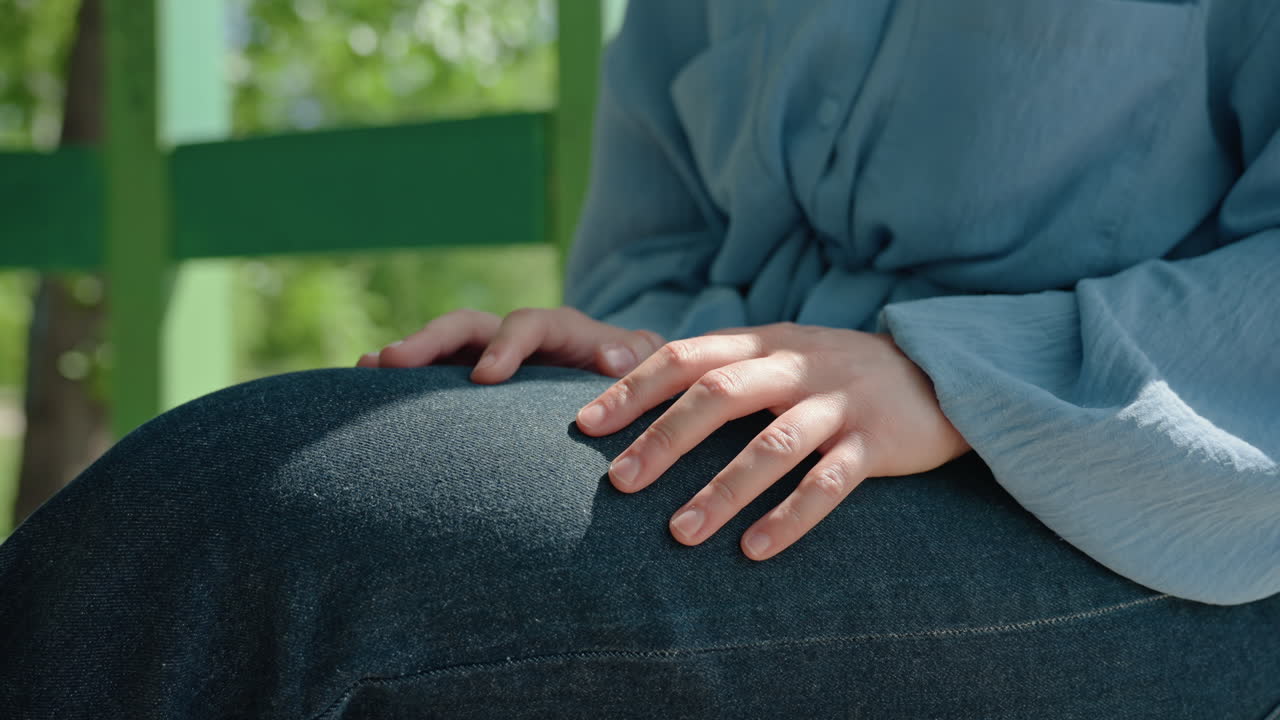 청바지를 입고 긴장한 표정으로 야외에 있는 여성의 모습. 공원 배경에서 불안감을 드러내는 데님 차림의 여성. 공원 환경에서 손가락으로 톡톡 치면서 불안감을 보이는 청바지 차림의 여성