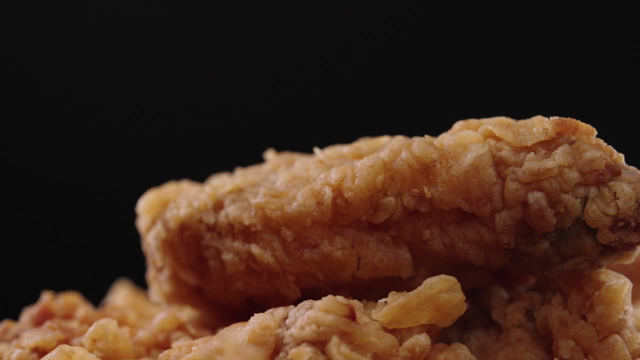 A close-up, slow-motion video capturing the tempting, crunchy layers of fried chicken, bringing out its golden-brown, crispy texture in stunning detail.