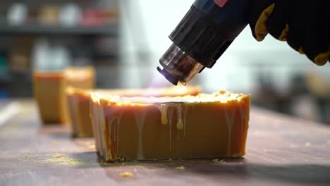 a close-up view of melting wax being heated with a hairdryer, showcasing the transformation of solid wax blocks into liquid for crafting purposes