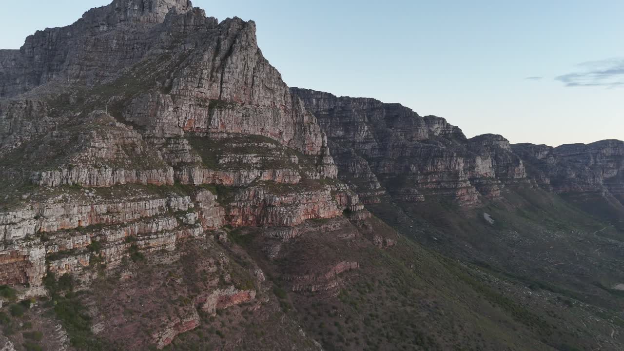 Sunset aerial shot of Table Mountain, Cape Town, South Africa, highlighting rugged cliffs, golden light