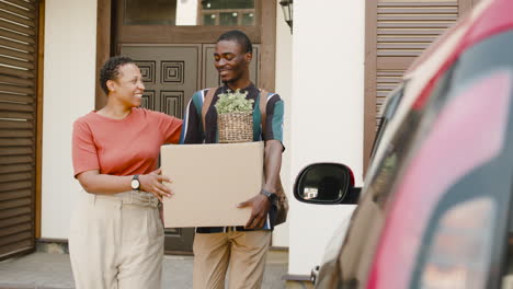 Young Man Holding Box Walking With His Mom Towards Car Before Moving Home 1