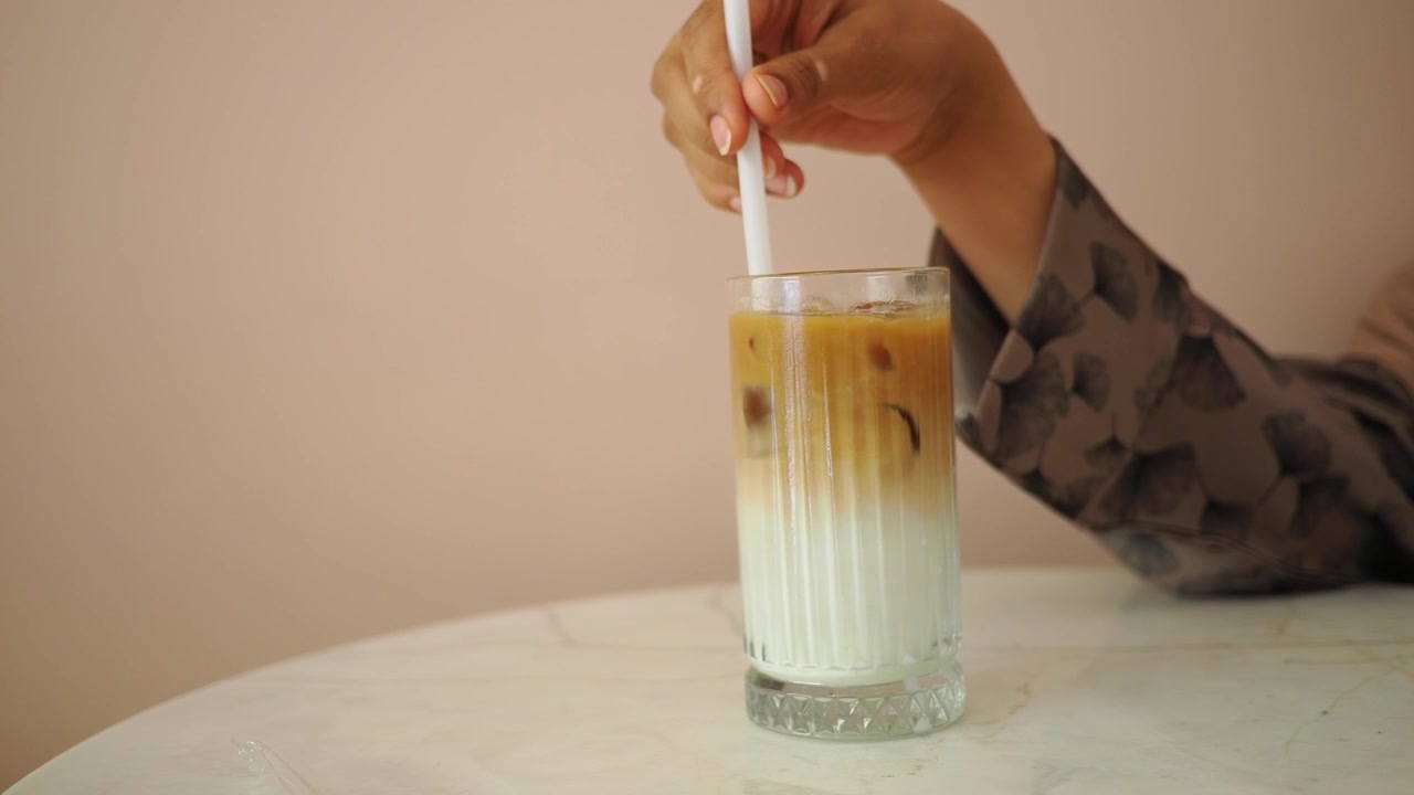 Persona che mescola caffè freddo in un bicchiere