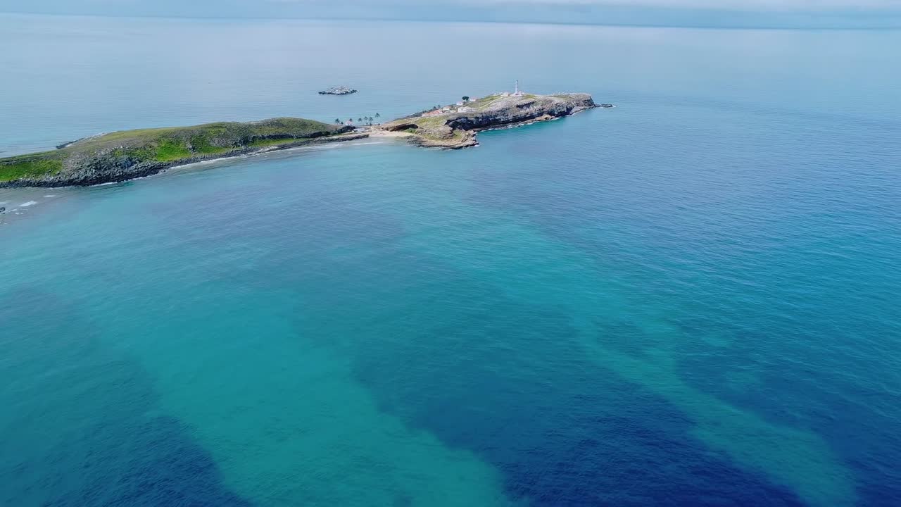Arcipelago di Abrolhos che mostra un vasto paesaggio aereo di isole rocciose immerse nelle acque limpide, turchesi e blu intenso dell'Oceano Atlantico in Brasile, sorvolo in avanti con drone