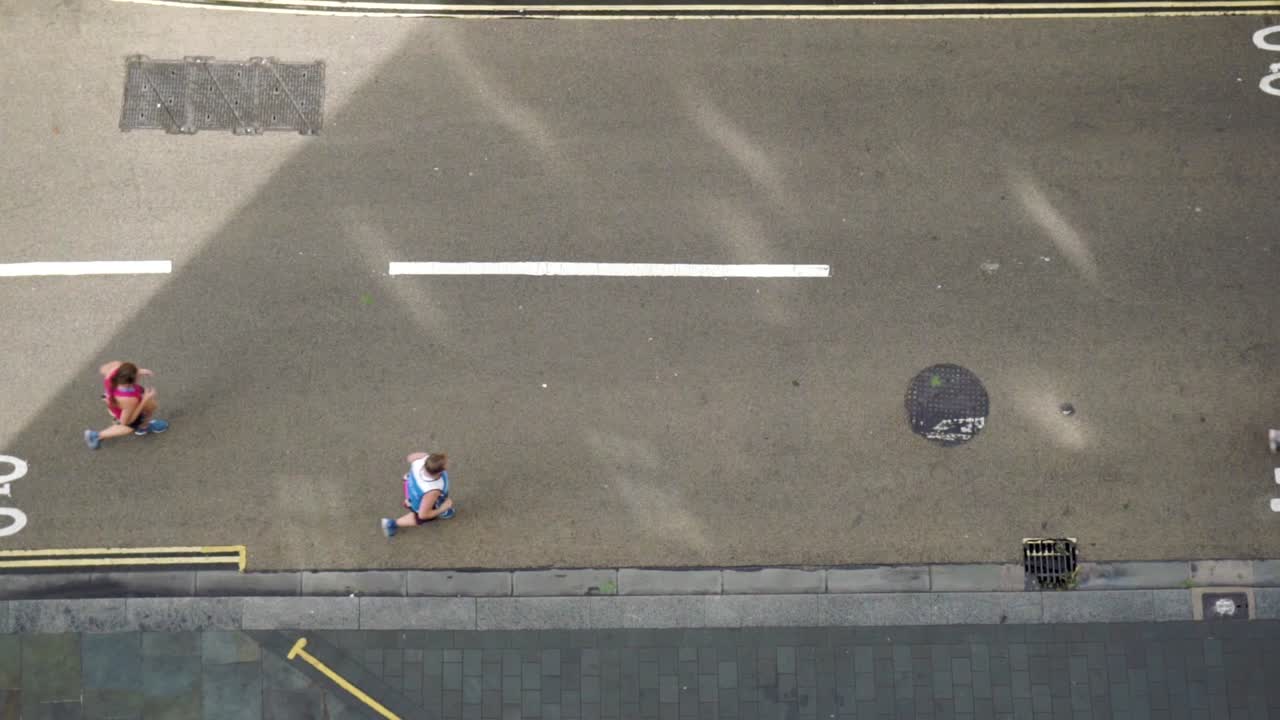 Slow motion aerial view of joggers on street