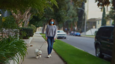 [cámara utilizada: canon c300] mujer caucásica con una máscara quirúrgica mientras paseaba con su perro