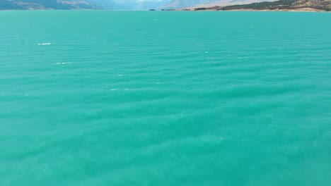 vista aérea con una inclinación de cámara lenta del lago pukaki, nueva zelanda, mientras volaba cerca del agua