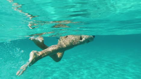 underwater shot of woman swimming on the surface in turquoise blue sea