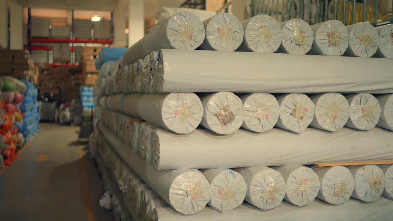 Rotoli di tessuto impilati su pallet all'interno di una fabbrica di produzione di tende