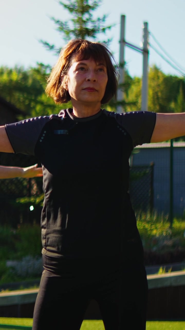 Donna matura che pratica yoga all'aperto alla luce del sole mattutino