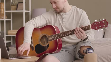 retrato de un hombre con una pierna protésica tocando la guitarra en casa