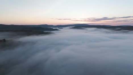 aerial sunset above the clouds , drone fly in unpolluted nature with mountains peaks above the fog in misty scenic countryside