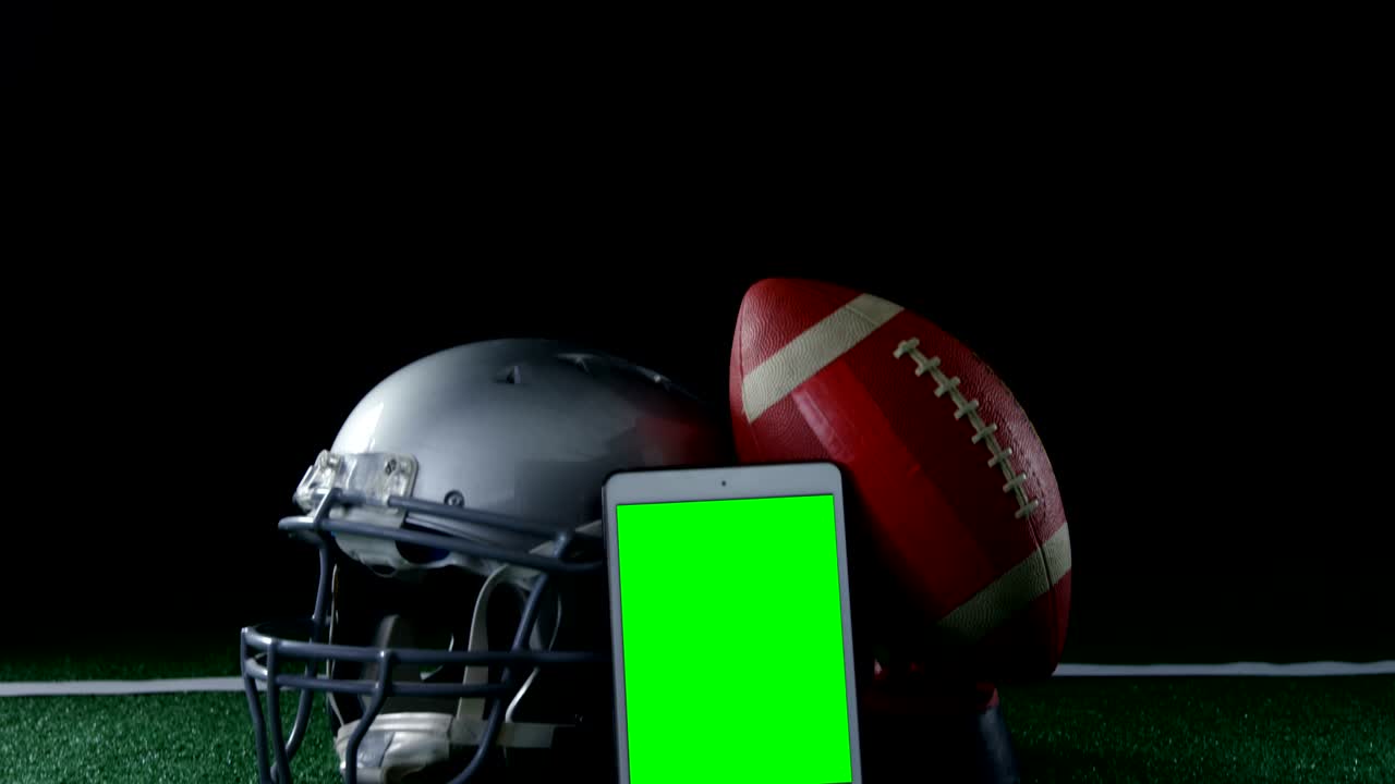 Primo piano di pallone, telefono cellulare e casco su campo in erba sintetica 4k