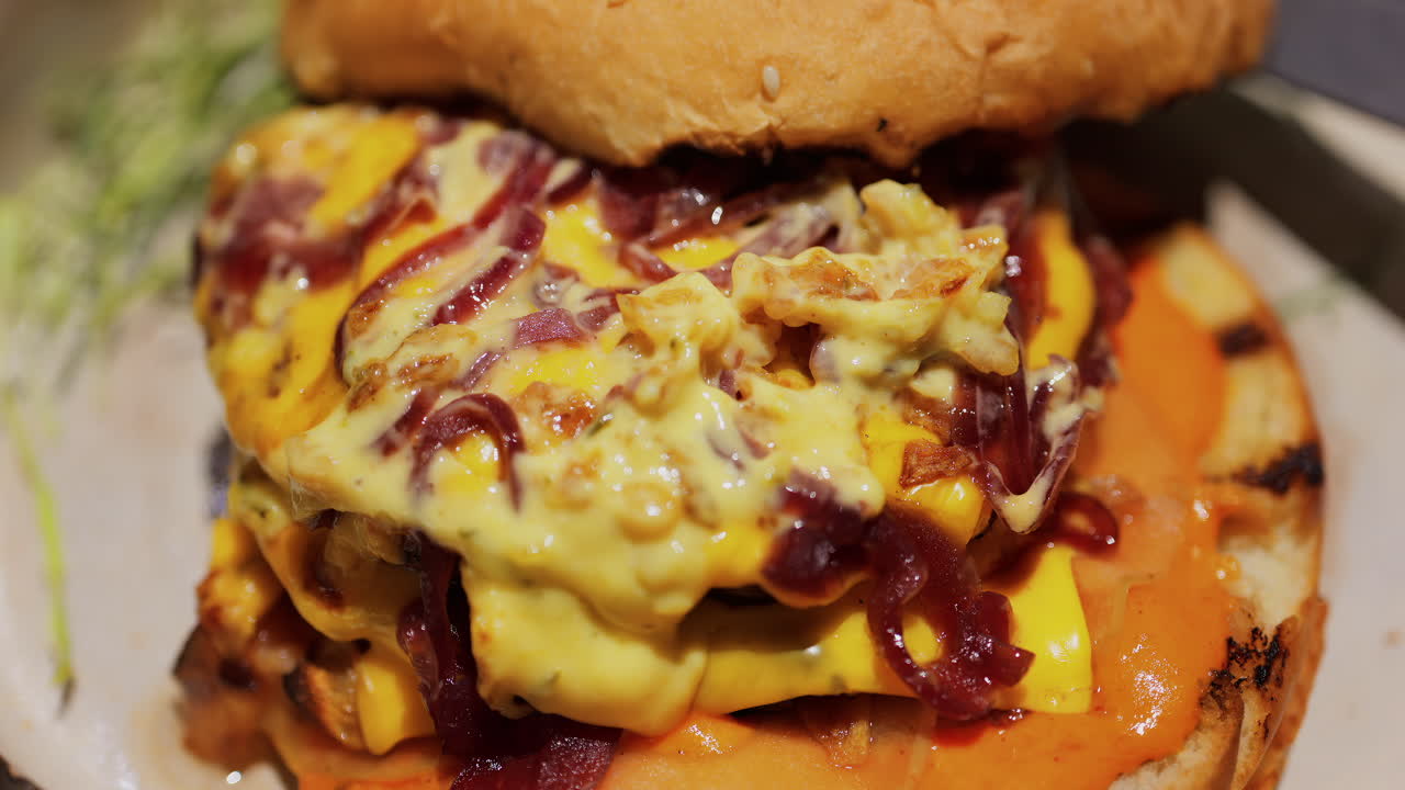 Close up of a loaded burger with melted cheese, caramelised onions, and a creamy sauce on a toasted bun