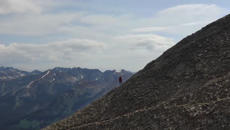 Person-standing-on-mountain-ridge-looking-out-at-landscape