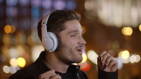 Excited-man-dancing-in-headphones-on-dark-city-street.-Happy-guy-enjoying-music.