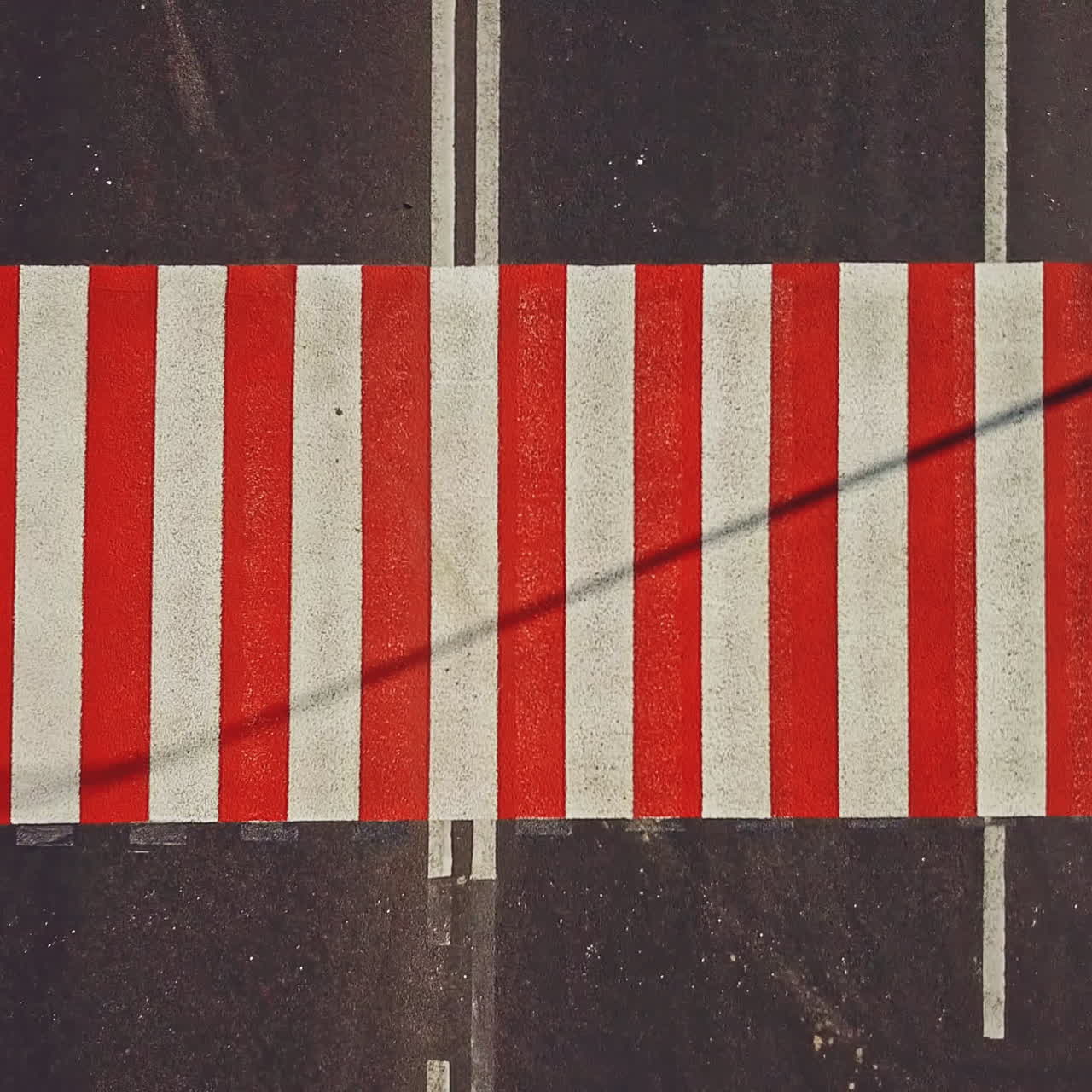 Road surface marking with red and white stripes and the cars driving on it. Pedestrian crossing on asphalt to convey official information for road safety traffic. Close-up