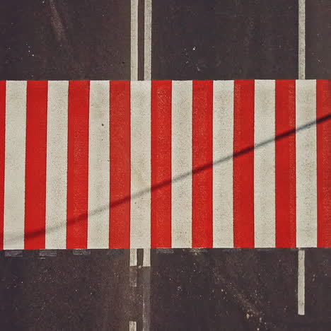 Road surface marking with red and white stripes and the cars driving on it. Pedestrian crossing on asphalt to convey official information for road safety traffic. Close-up